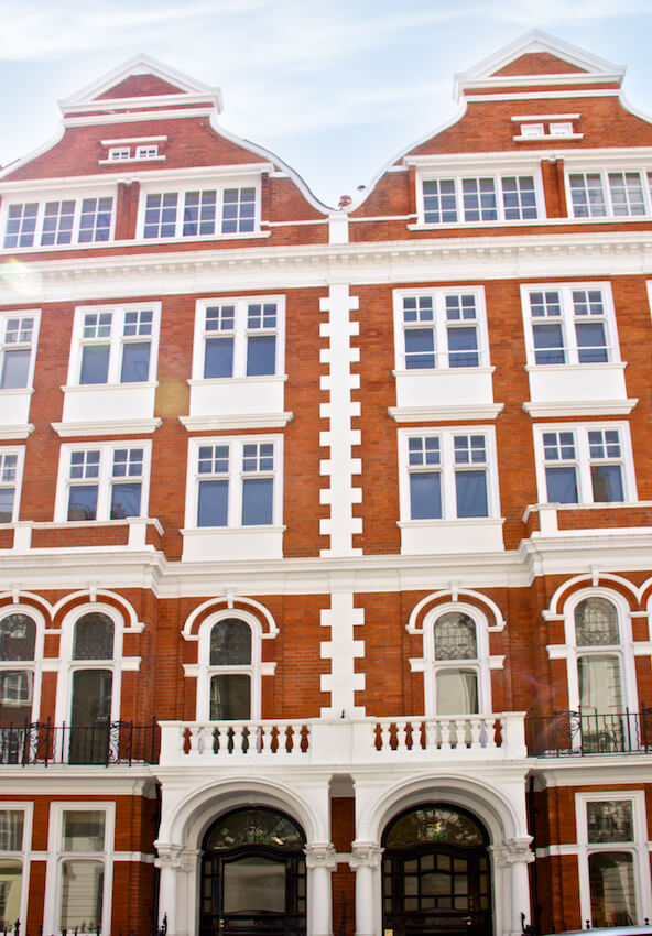 White sash windows on a traditional red brick building, showing the arched black doors